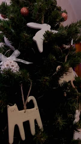 Christmas ceramic animal-shaped ornaments on a Christmas tree with lights close-up as a background