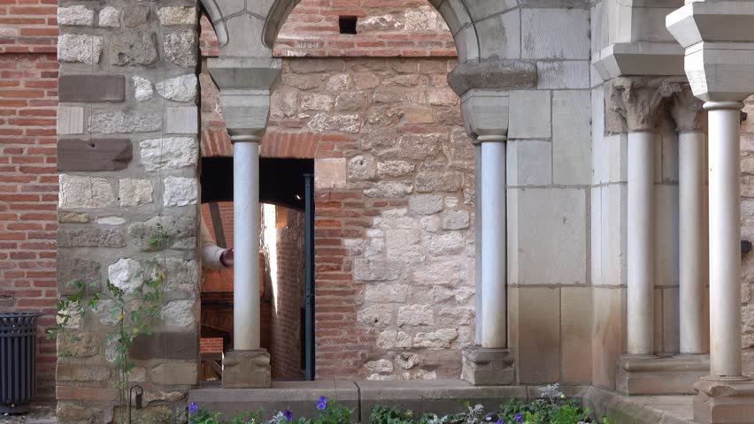 Two eldery people peek and kiss in a stone courtyard