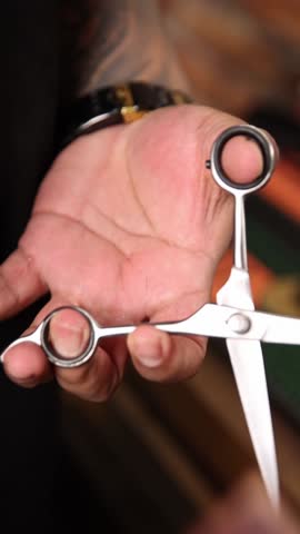 The barber is working. He is cutting hair in the barber shop.
