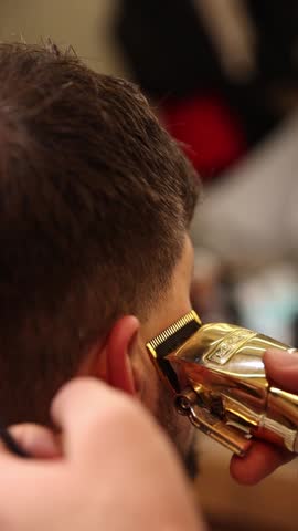 The barber is working. He is cutting hair in the barber shop.