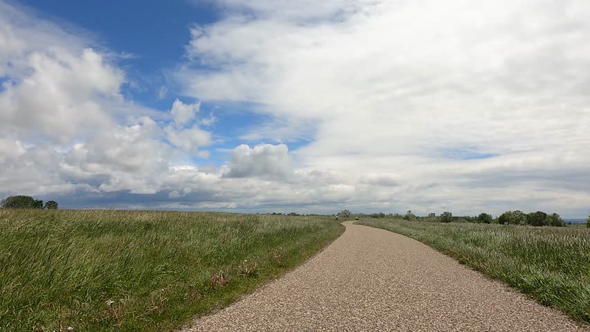 Beautiful aerial footage capturing a road connecting to a horizontal sky with soft clouds, paired with gentle glass pieces or objects blowing across the ground.