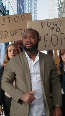 Vertical Video People and activists protesting against corruption during a public march, holding signs and banners to demand justice and transparency. political protest driven by anger and awareness