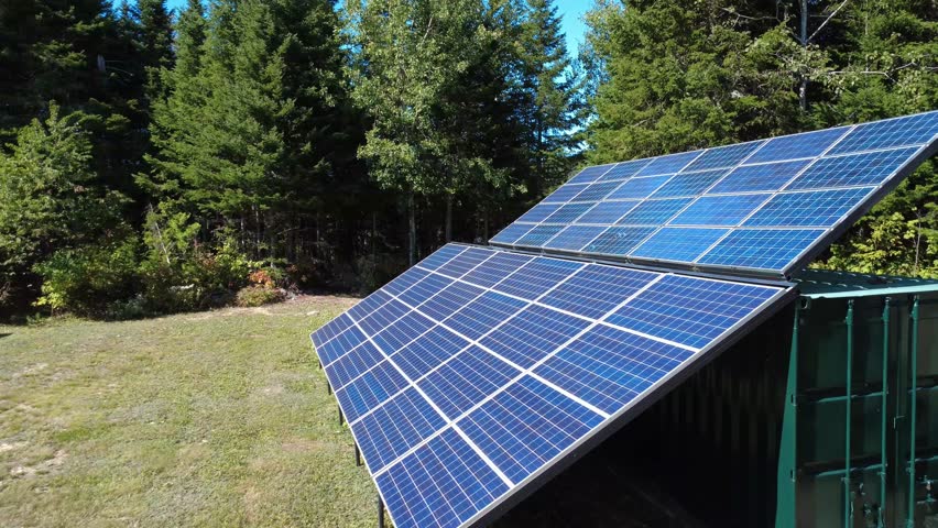 Close flyover above a series of solar panels with bluish photovoltaic cells capturing the sun