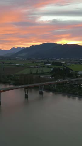 Stunning Sunset Over a River Bridge, Mountains, and Agricultural Fields in British Columbia, Canada