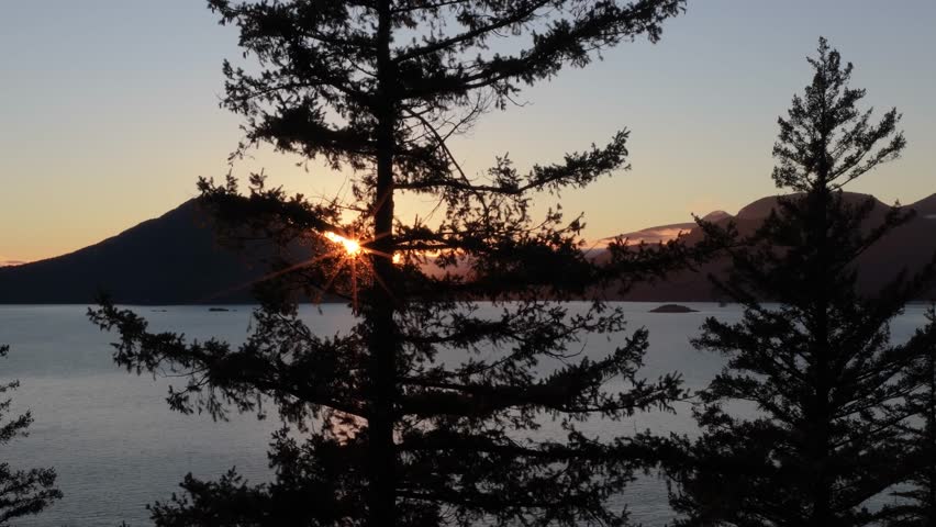 Golden Sunrise Beams Over Tranquil Waters and Majestic Mountains in British Columbia, Canada