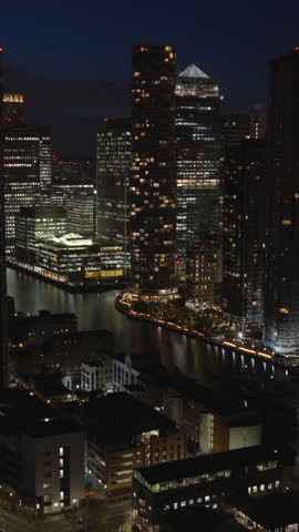 Vertical aerial view of Canary Wharf in London at night. Illuminated financial district located on the Isle of Dogs