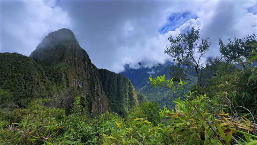 Huayna Picchu Quechua Mountain Machu Picchu lush green jungle prominent Peruvian Andes Peak Peru Perú aerial drone sunny blue sky clouds rainy season historic Inca Sanctuary landscape pan