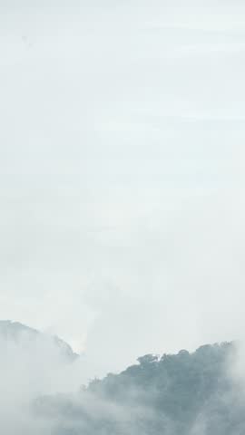Misty mountain peak with dense tropical forest and moving clouds at Lio Mountain, Brebes, Indonesia.