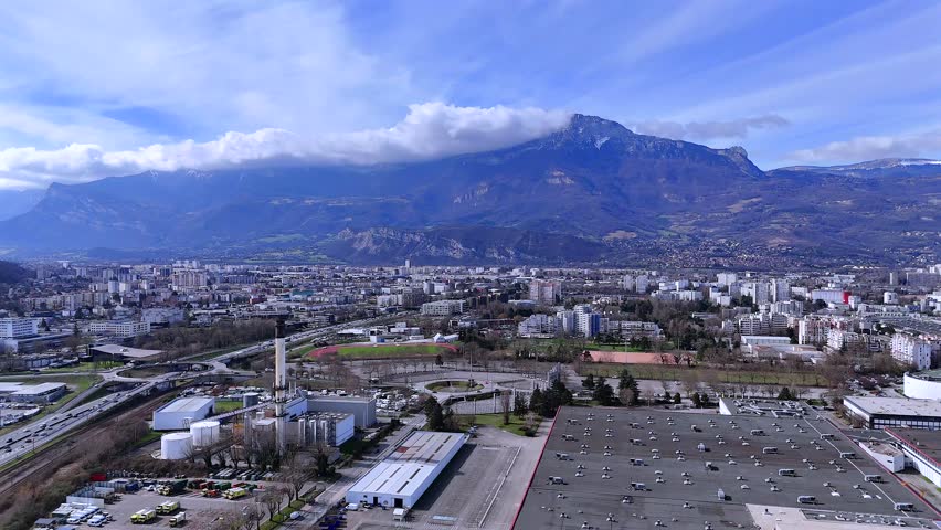 Aerial panorama Grenoble with roundabout sports fields and mountains