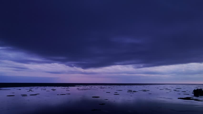 Aerial of lake at dusk with dark storm clouds and violet hues filling the sky