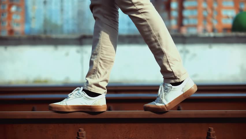 Male Feet Shoes Stepping Along Railway Track. Walking And Balancing On Rusty Metal Railings. Life Path Choice And Finding Balance. Walking On Edge. Suburban Transportation Footwear. Goal Direction.