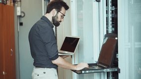 IT Specialist Or System Administrator Working In Data Center Server Room. Technician Using Laptop Typing On Terminal Keyboard While Monitoring Network Hardware. Cyber Security Expert Checking Server - Powered by Shutterstock - Get 15% off with code: PIKWIZARD15