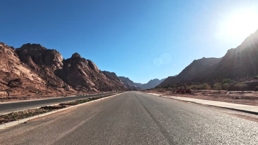POV drive through rocky canyon highway with bright sunlight and clear blue sky