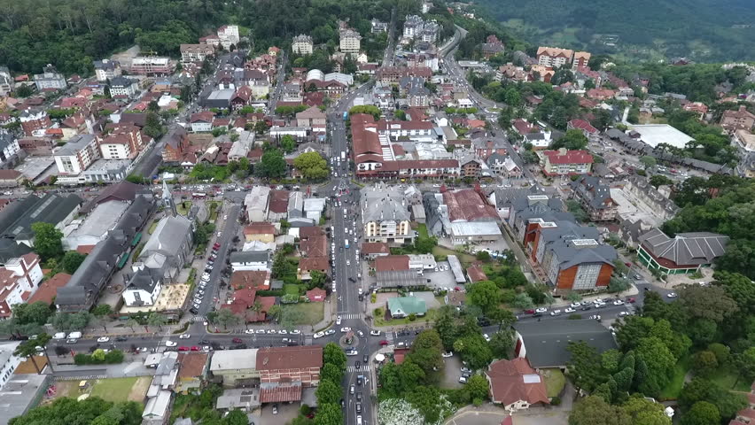 Cinematic drone aerial high altitude establishing shot revealing downtown Gramado city center and tilting up to the distant valleys and mountains in Rio Grande do Sul Brazil. High quality 1080p video.
