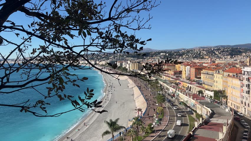 Nice Promenade des Anglais establishing shot from hillside viewpoint showing Bay of Angels, Mediterranean coastline and dense urban seafront in Nice France.