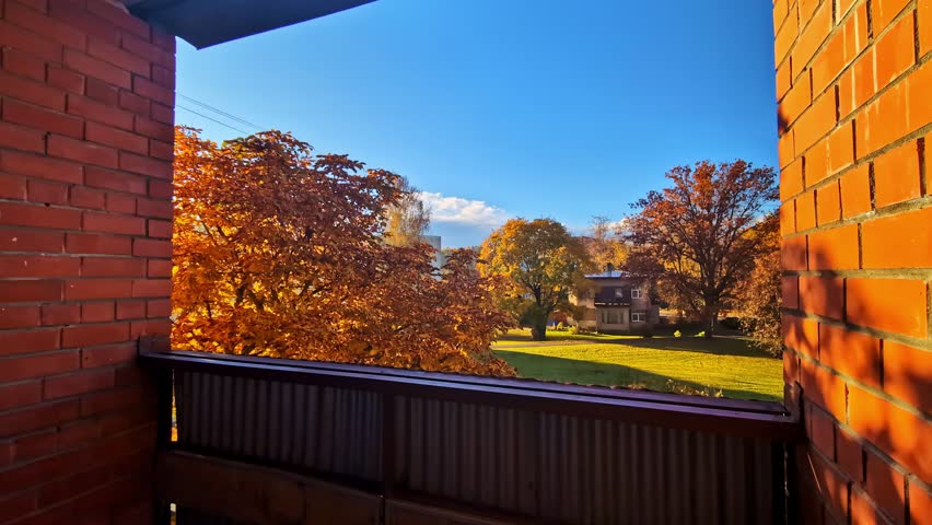 Suburban view with autumn trees and residential house from balcony, sunny day