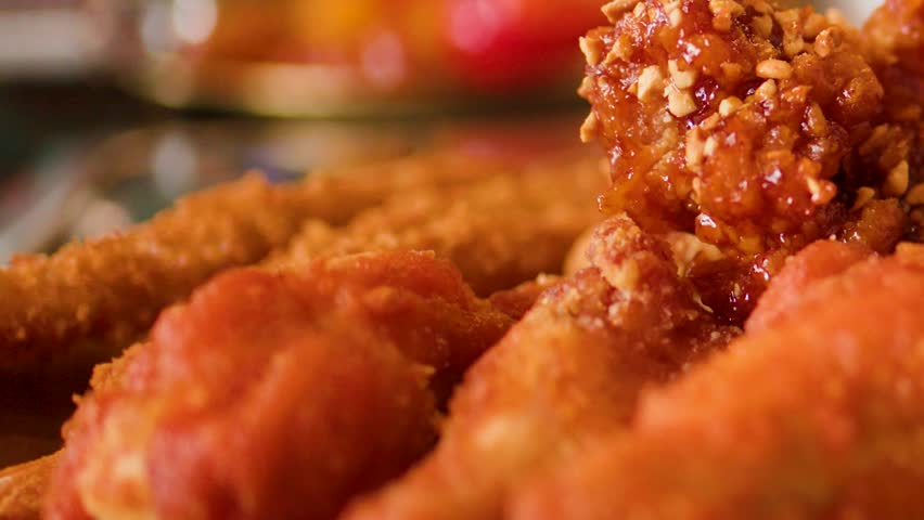 Macro shot of golden fried chicken pieces coated in spicy sauce with selective focus.