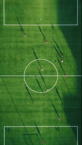Soccer match on green field at sunset light 