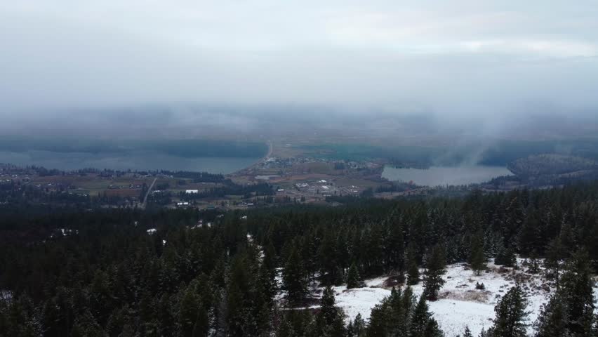 Canadian Winter Landscape over Forest Trees above valley lakes in Lake Country British Columbia. Low fog and clouds on gloomy winter day.