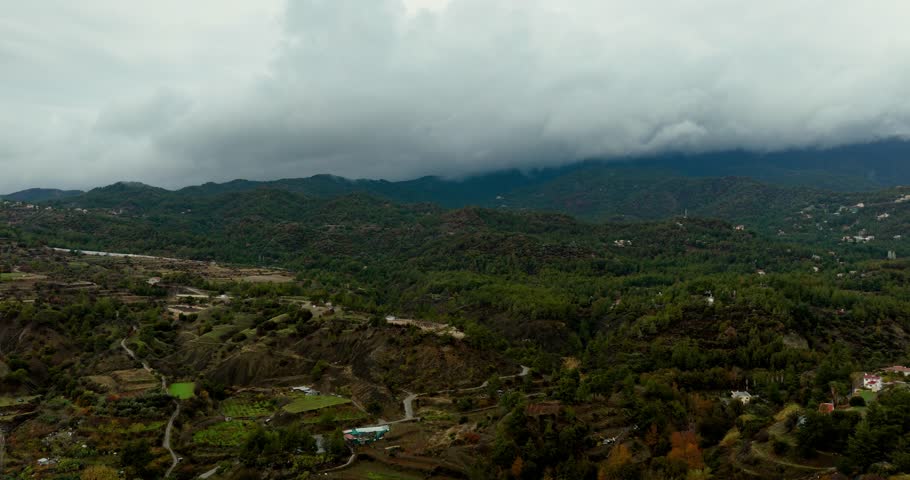 Drone flyover towards cloud covered Troodos Mountains and Mount Olympus