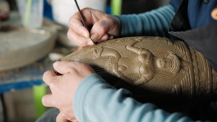 Close up of artisan hands sculpting relief on a piece of raw clay pottery. Handmade concept. Siem Reap, Cambodia