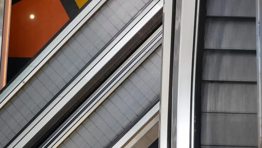 An empty escalator. Escalators in a large multi-storey shopping mall. People are riding a travelator in a huge supermarket. Different floors of a multi-storey building.