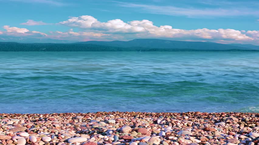 a beautiful pebble beach and mountain peaks on the horizon