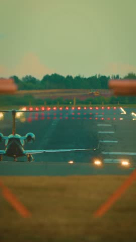 Jet accelerating on runway with turbines spinning and lights glowing. Private aircraft speeding on airstrip with landing gear rolling and navigation lamps shining, vertical orientation. Business jet