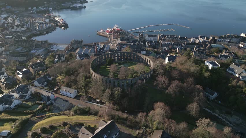 Beautiful aerial view of Oban, Scotland on a sunny winter day. Drone orbit around McCaig’s Tower.