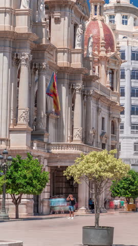 Valencia City Hall (Ajuntament de Valencia) timelapse in Plaza de Ayuntamiento. Historic building entrance tower under a blue sky. People strolling the main square in Spain