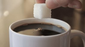 Slow Motion Hand Dropping Sugar Cube Into Black Coffee. Sugar Falling Down Into Coffee Cup. Coffee Caffeine Addiction Junk Food. Concept of Unhealthy Eating, Diabetes, Obesity, Heart Disease.  - Powered by Shutterstock - Get 15% off with code: PIKWIZARD15
