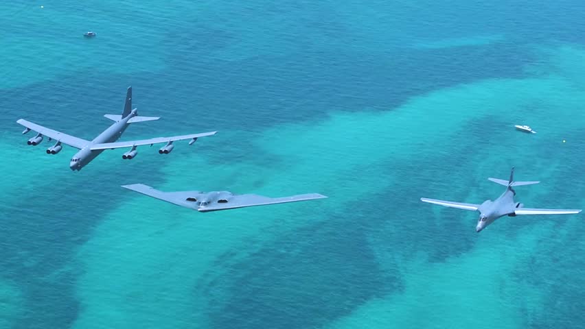Strategic bomber formation flies over turquoise waters, demonstrating joint airpower, stealth, and long-range deterrence capability.
