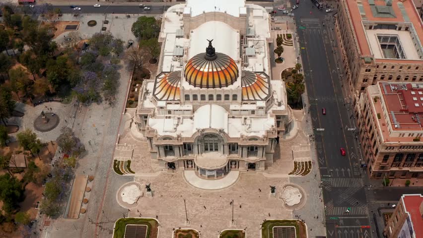 Forward fly aerial shot of the Palace of Fine Arts, Palacio de Bellas Artes, with its colorful dome in historic Mexico City, Mexico.