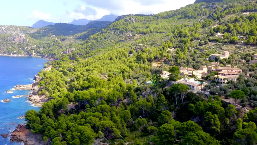 Aerial view of Mallorca, Spain, showcasing a stunning tropical coastline with turquoise waters, beaches, and lush landscapes on a sunny summer day.
