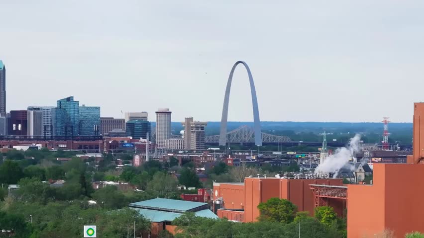Aerial view of St. Louis, Missouri, featuring the iconic Gateway Arch surrounded by urban buildings, lush greenery, and historic cityscape.