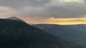 This captivating time-lapse video captures the mesmerizing sunset over the majestic Karkonosze Mountains in southwestern Poland, part of the Sudetes range. As the sun dips below the horizon, vibrant hues of orange, pink, and purple paint the sky, with clouds drifting gracefully across the rugged peaks and valleys. Filmed in crisp Full HD (1080p) resolution, this footage showcases the natural beauty of this UNESCO-listed area, including hints of alpine forests and distant horizons. Ideal for travel documentaries, nature videos, relaxation content, environmental campaigns, or background visuals in commercials and social media. The smooth acceleration highlights the serene transition from day to night, evoking feelings of peace and wonder. No people or artificial elements – pure wilderness. Duration: 35 seconds. Perfect for evoking tranquility and adventure. - Powered by Shutterstock - Get 15% off with code: PIKWIZARD15