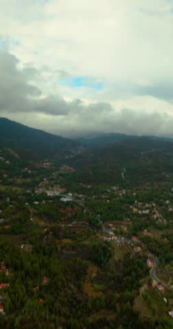 Vertical aerial drone view of Troodos Mountains landscape with clouds and rural valleys in Cyprus
