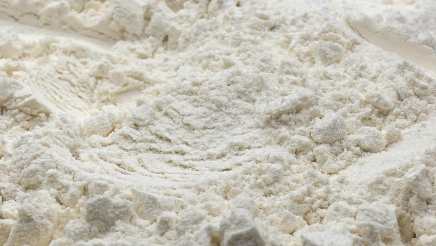 Close up of raw wheat flour being scooped for baking