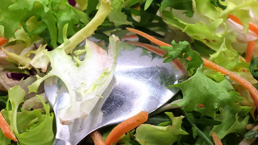 Fresh mixed green salad with carrots and a silver spoon