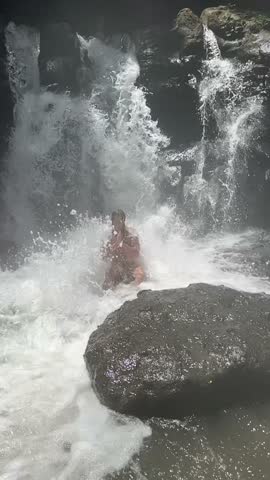 Man Observes Fierce Cascading Waters, Person Relaxes Amidst Roaring Torrents And Splashing Spray, Person Sits Underneath Thunderous Waterfall Surrounded By Crashing Waves And Misty Spray