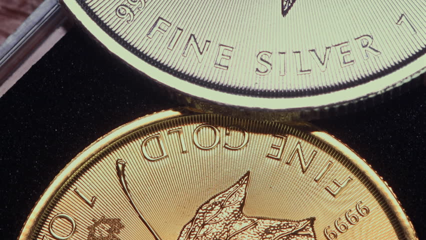 Close-up of the inscription “fine silver” on a silver coin lying on a gold coin labeled “fine gold,” representing precious metal prices and the gold-to-silver ratio.