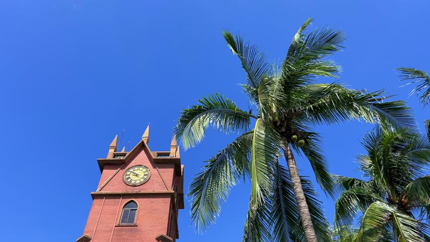 Hainan, China, June 15, 2025: Haikou Clock Tower is a clock tower in Haikou, near the Haidian River, in the northern part of Boai Road, west of the Renmin Bridge. The tower is made of red brick. 4К