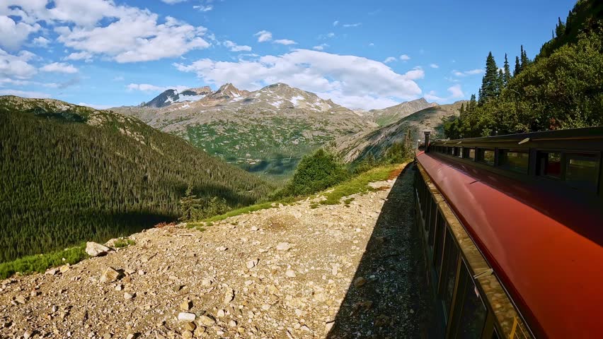 Alaska wilderness from White Pass and Yukon railroad train ride between Skagway Alaska and Whitehorse Yukon Canada. Beautiful sunny day with white clouds and blue sky