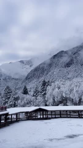 Vertical 1080p video of a serene winter landscape in a mountainous region of China.Dynamic mist movement over the mountains