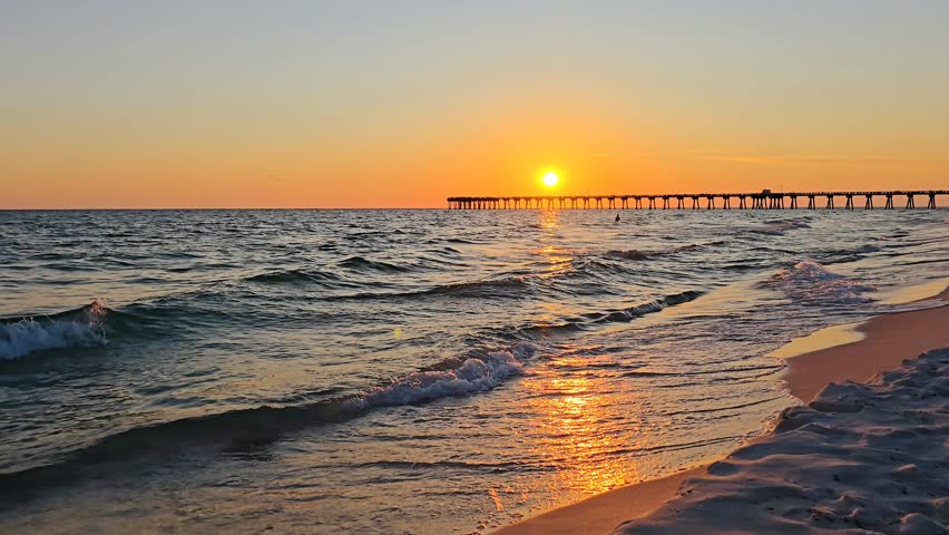 Scenic ocean waves at beautiful sunset with pier in the background