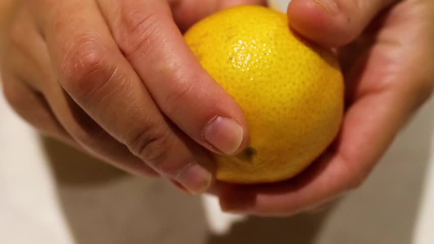 A detailed close-up shot of hands carefully removing the peel from a ripe orange.