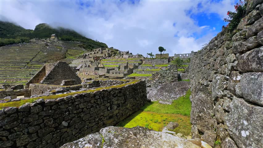 Shihuahuaco tree Machu Picchu sunny blue sky clouds morning Peru Perú aerial drone mount Huayna Picchu rainy season lush green Peruvian Andes Inca Temple Sanctuary jungle stone work terrace pan left