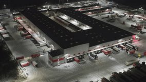 Aerial Night View of Large Logistics Distribution Center with Multiple Loading Docks | Semi-Trucks at Warehouse Ramps in Snowy Winter | Industrial Freight Hub Operations and Cargo Sorting Facility - Powered by Shutterstock - Get 15% off with code: PIKWIZARD15
