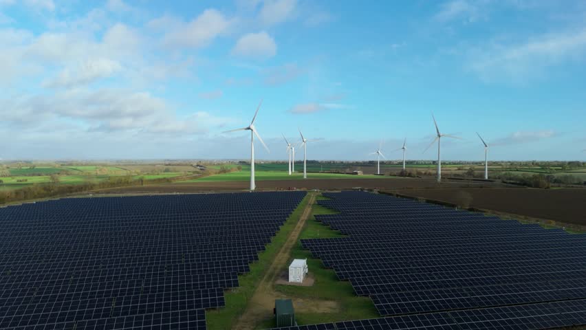 Aerial drone view of solar power panels and wind turbines for renewable energy generation in rural landscape near Melton Mowbray United Kingdom