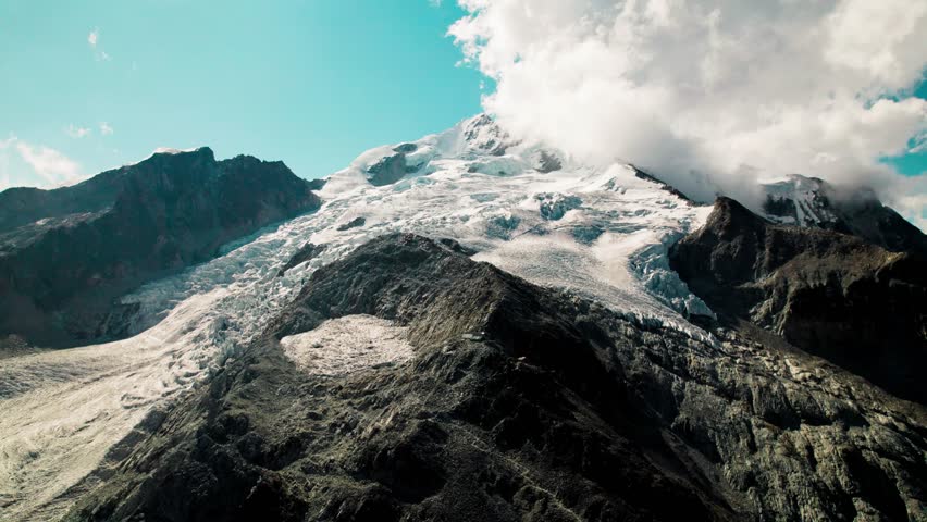 A sprawling glacier descending the rugged face of Huayna Potosí. The shot highlights the contrast between white ice and dark volcanic rock in the Bolivian Andes.